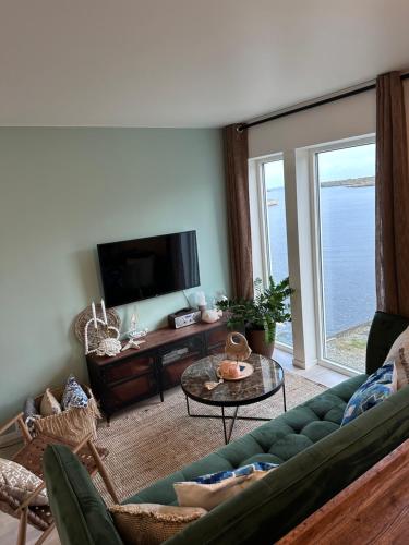 a living room with a green couch and a tv at New Åkrahamn coast house in Sæveland