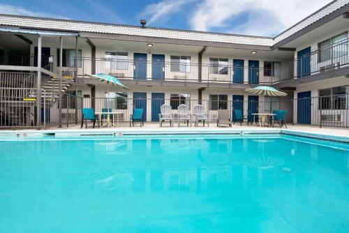 a pool in front of a hotel with chairs and tables at Studio 6 Grand Junction, CO in Grand Junction