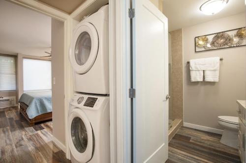 a bathroom with a washer and dryer next to a bed at 126 Hale Kamaole in Wailea