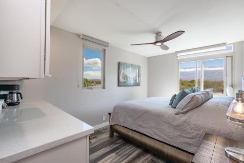 ein weißes Schlafzimmer mit einem Bett und einer Küche in der Unterkunft 401 Nani Kai HaleBeachfrontNewly Remodeled in Kihei