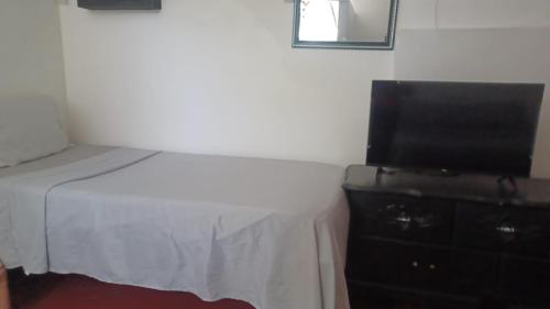 Dormitorio con cama y tocador con TV en Drifters@One Mile en Negril