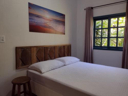 a bedroom with a bed and a window at Casa com lindo jardim, um recanto a 100 metros da praia in Porto Belo