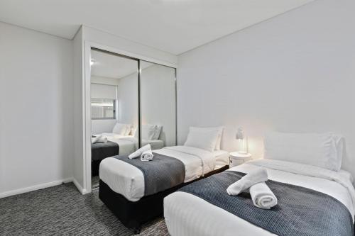 Pokój hotelowy z 2 łóżkami i lustrem w obiekcie AAN Apartments North Sydney w mieście Sydney