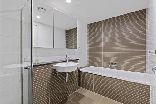 uma casa de banho com um lavatório e uma banheira em AAN Apartments North Sydney em Sydney