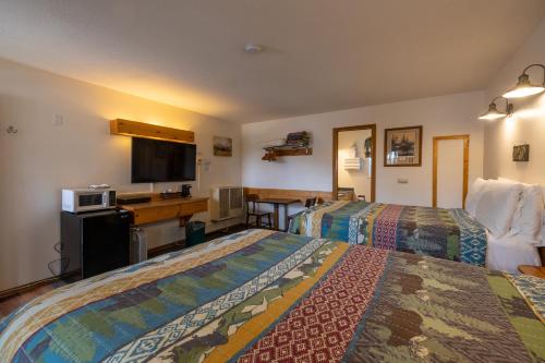 a hotel room with two beds and a flat screen tv at Elk Horn Lodge in Cooke City