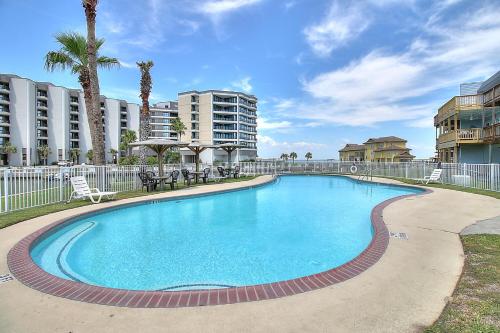 a swimming pool in a resort with palm trees and buildings at Bay Tree D2 in Port Aransas