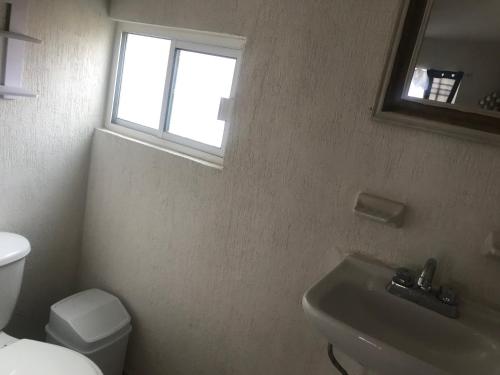 a bathroom with a toilet and a sink and a window at Casa vacacional in Isla La Piedra