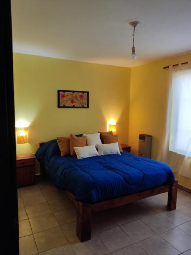 1 dormitorio con 1 cama grande con sábanas azules en El Aromito en Alta Gracia