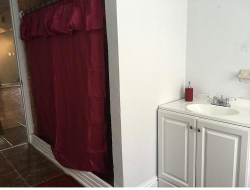 a bathroom with a sink and a red shower curtain at Miami House in Miami