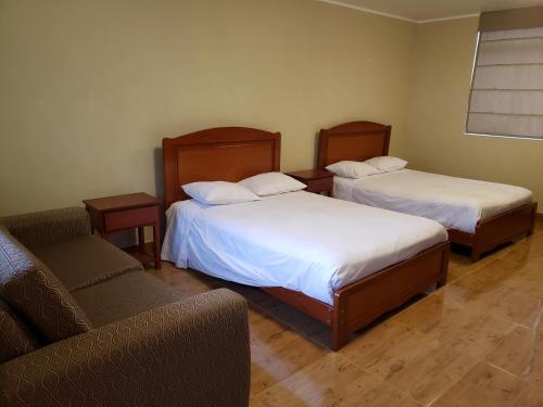 Habitación con 2 camas, silla y sofá en Condominio La Curva en Churín
