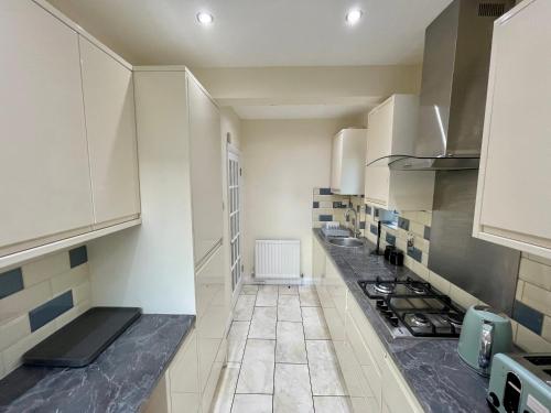 a kitchen with white cabinets and a stove top oven at Paul Properties in Ruislip