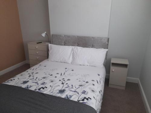 Schlafzimmer mit einem Bett mit einer schwarzen und weißen Bettdecke in der Unterkunft Chorlton Apartments in Sale