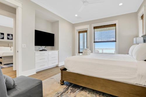 a white bedroom with a large bed and a tv at Macon Memories in St. George Island
