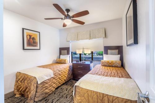 a bedroom with two beds and a ceiling fan at Scottsdale Camelback Resort in Scottsdale
