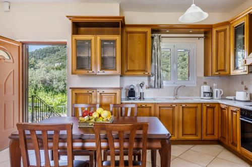 a kitchen with wooden cabinets and a table with a bowl of fruit at Eleonora's in Skopelos Town