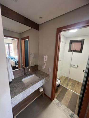 a bathroom with a sink and a toilet and a mirror at Resort Quinta Santa Bárbara in Pirenópolis