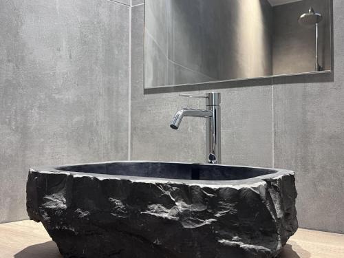 um lavatório de pedra preta numa casa de banho com espelho em Bigaro II em Heers