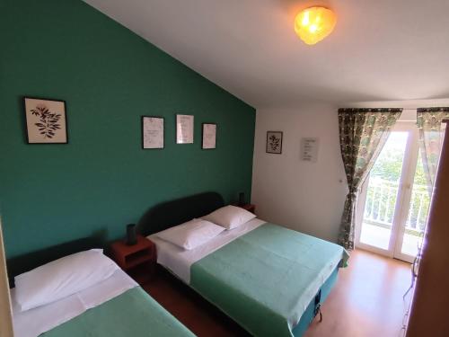 1 Schlafzimmer mit 2 Betten und einer grünen Wand in der Unterkunft Apartments by the sea Tribunj, Vodice - 12144 in Tribunj