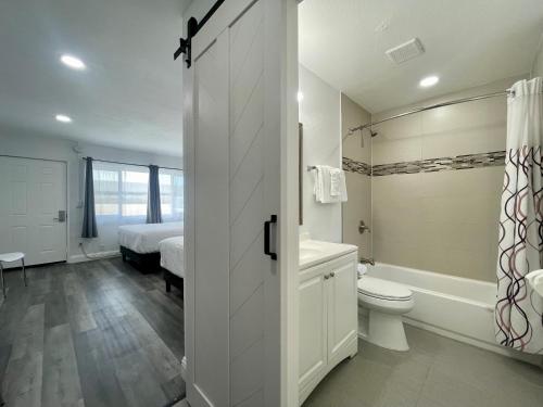 a white bathroom with a bed and a toilet and a tub at Budget Inn in Lompoc