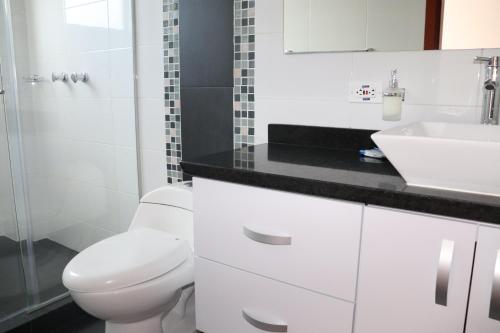 a white bathroom with a toilet and a sink at Suite La Colina - Norte - Pasto in Pasto