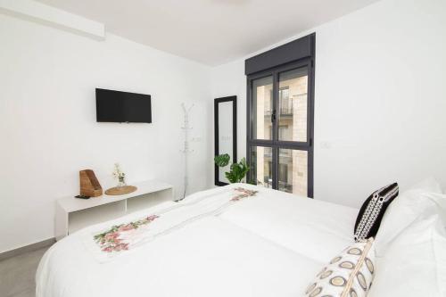 a white bedroom with a white bed and a window at Agrippas Suite 6 in Jerusalem