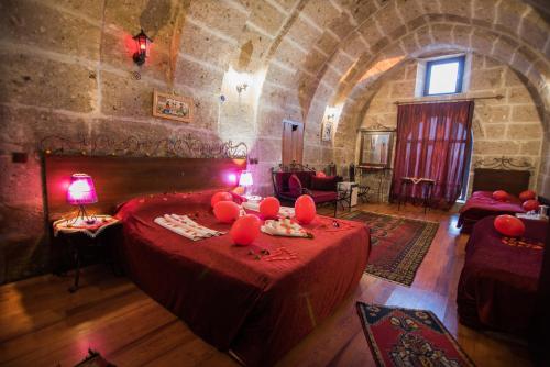 a room with a bed with red pillows on it at Kapadokya Ihlara Konaklari & Caves in Guzelyurt