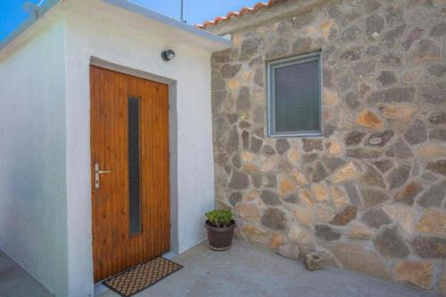 ein Steingebäude mit einer Holztür und einer Pflanze in der Unterkunft Family friendly house with a swimming pool Vadalj, Primosten - 21379 in Vadalj