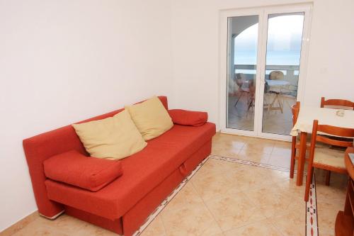 a red couch in a living room with a balcony at Apartments by the sea Lun, Pag - 3320 in Lun