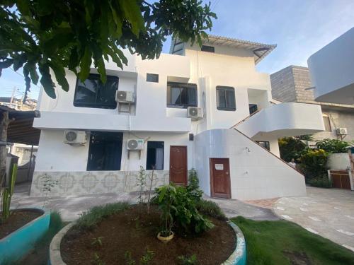 una casa blanca con una escalera de caracol delante de ella en Hostal Brisas Del Mar, en Puerto Villamil