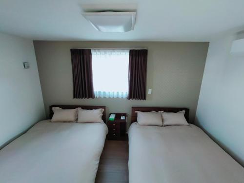 two beds in a small room with a window at FunHome黒川 in Nagoya