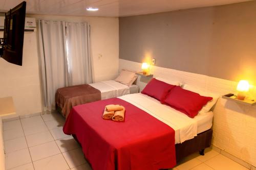 a hotel room with two beds and a red blanket at Noronha Economy Suítes - Hospedagem com melhor localização e custo benefício da ilha in Fernando de Noronha