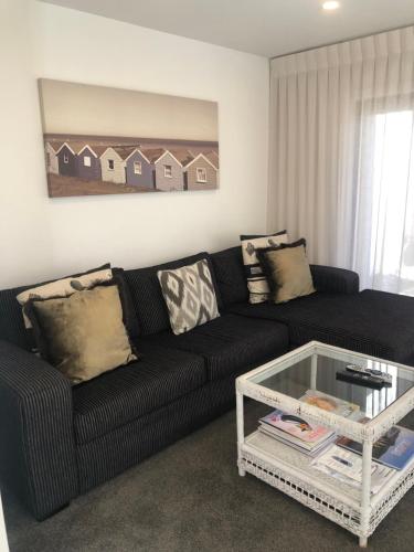a living room with a black couch and a coffee table at The Bay The Beach The Mount The Best in Mount Maunganui