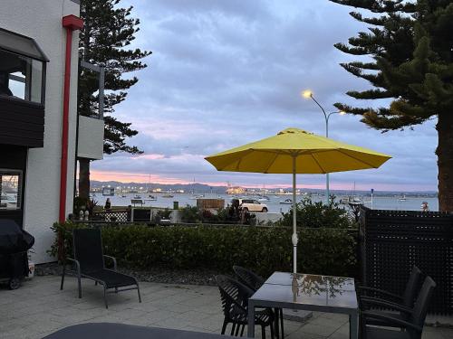 a table with a yellow umbrella on a patio at The Bay The Beach The Mount The Best in Mount Maunganui