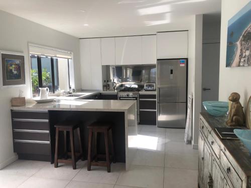a large kitchen with a counter and a refrigerator at The Bay The Beach The Mount The Best in Mount Maunganui