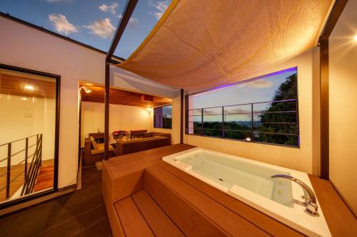 a large bathroom with a tub with a large window at クリスタルヴィラ南城 in Azama