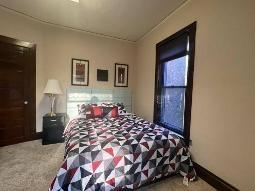 a bedroom with a bed with a checkered blanket and a window at Bel apartment in Sioux City