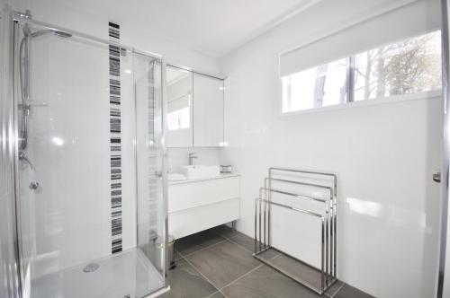 a white bathroom with a shower and a sink at Happy Tides in Beachmere