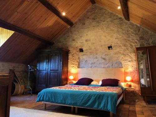 1 dormitorio con 1 cama en una pared de piedra en Grande maison familiale, rustique et charmante en Bourgogne, dans le Morvan, en Dun-sur-Grandry