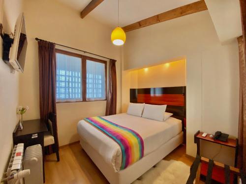 a bedroom with a bed with a rainbow blanket at Mistico San Blas Boutique in Cusco