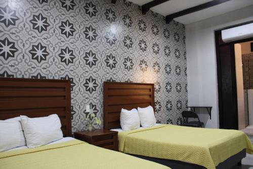 a hotel room with two beds and a wall at Hotel Guaranducha Inn in Campeche