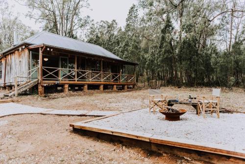 a wooden cabin with a table and chairs in front of it at Black Springs - A Romantic Bushland Escape in Mudgee