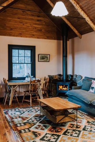 a living room with a couch and a table and a fireplace at The Gully - Dreamy Cabin on Acres of Outback Charm in Mudgee