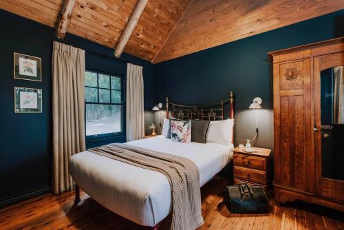 Eurunderee的住宿－The Gully - Dreamy Cabin on Acres of Outback Charm，一间卧室配有一张带蓝色墙壁的大床