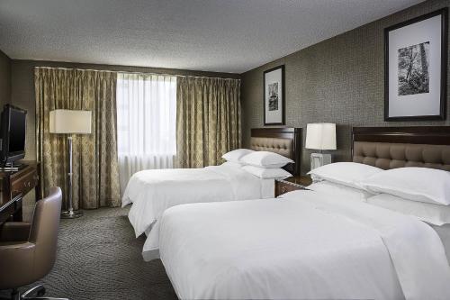 a hotel room with three beds and a television at Sheraton Oklahoma City Downtown Hotel in Oklahoma City