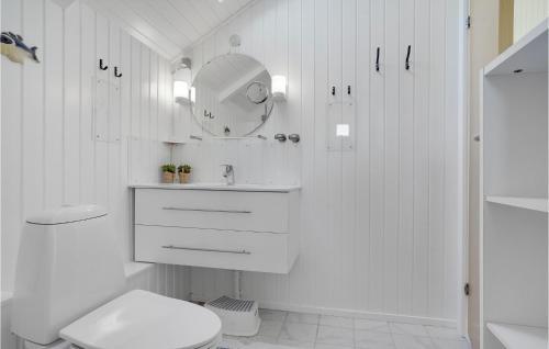 a white bathroom with a toilet and a mirror at Åbo in Klitmøller