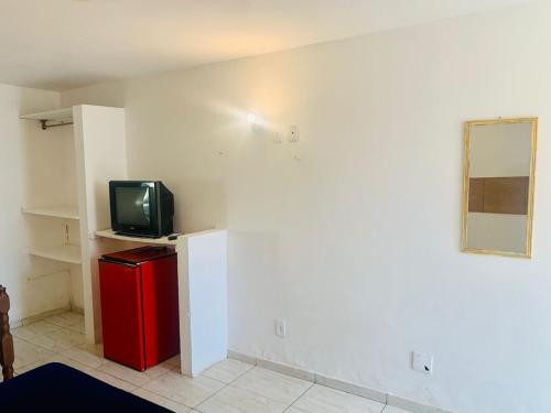 a room with a small television and a red refrigerator at Suite familiar completa in Búzios