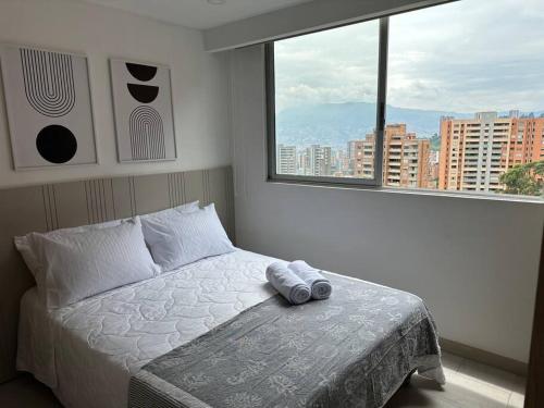 um quarto com uma cama e uma grande janela em Apto con bella vista-poblado 1510 em Medellín