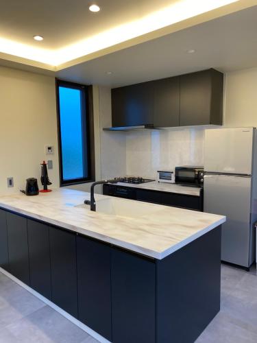 a kitchen with a large counter top with a refrigerator at Sky Blue Villa沖縄 in Jima