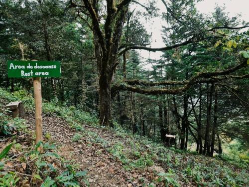 a sign on a trail in a forest at Cabaña El Descanso #1, Macho Mora Mountain Lodge in Alaska