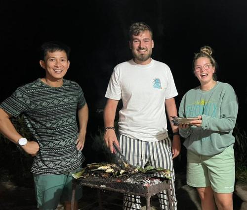 a group of three people standing next to a grill at NUANSA HOMESTAY Authentic&Hospitality in Rantepao